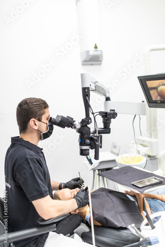 The dentist examines the patient's teeth with a dental microscope. Modern medical equipment