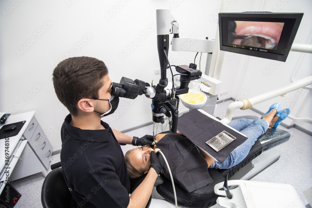 Male dentist examining woman looking on the teeth with professional microscope in the dental office Male dentist examining woman looking on the teeth with professional microscope in the dental office