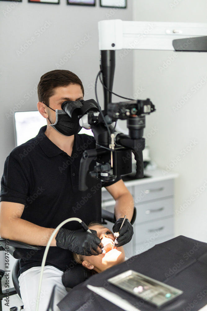 Dentist checking up patient teeth at dental clinic office. Microscope, professional dental treatment