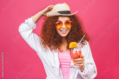 Photography Happy beautiful woman in summer casual clothes with a glass of cocktail drink studio shot isolated on colorful pink backgroud