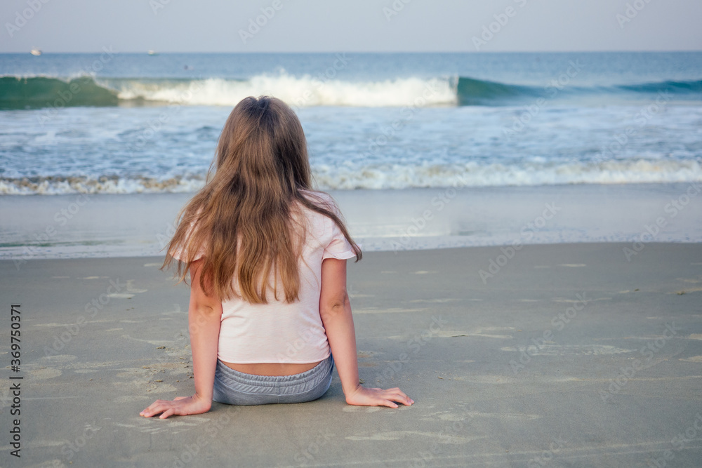 young girl sit on sand and looking at water young girl sit on sand and looking at water