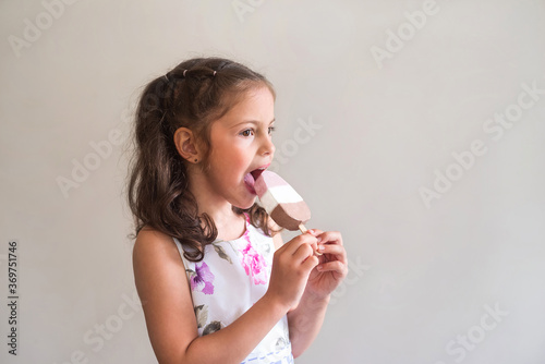 A little girl eats ice cream. The child bites with pleasure the summer dessert