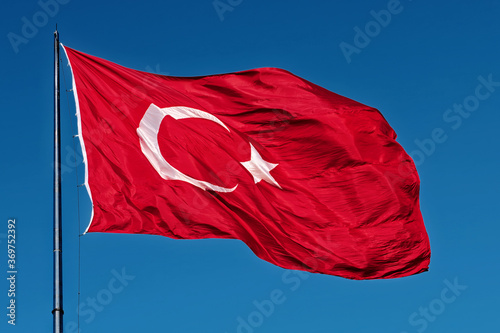 Turkish national flag waving in blue sky.