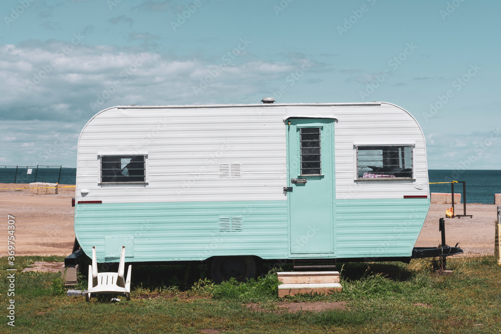 Camping on the beach in a vintage turquoise and white caravan trailer.