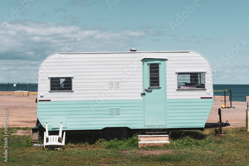 Camping on the beach in a vintage turquoise and white caravan trailer.