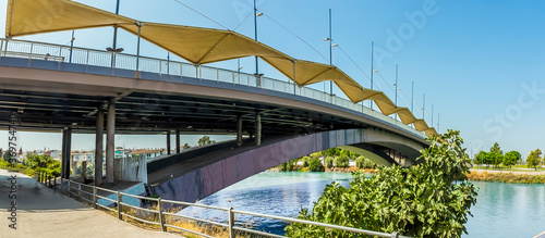 A view across the river Guadalquivir towards the Puppy Bridge in Seville, Spain in the summertime photo