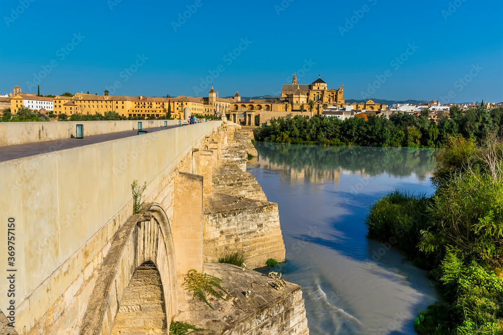 A view along the side of the Roman bridge leading into the ancient city of Cordoba, Spain in the summertime