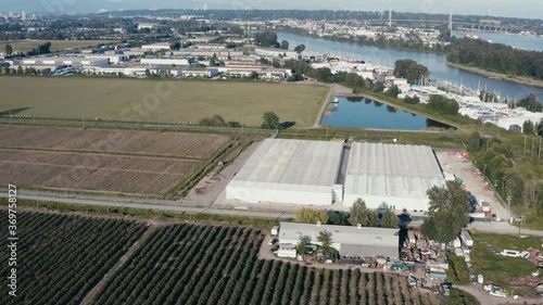 Aerial flyover medicianl grade cannabis marijuana plant processing greenhouse on a sunnay day property thats bob wired and gated with Governement regulated security staff in Richmond BC Canada 1-2 photo