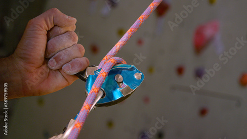 CLOSE UP: Unrecognizable belayer helps a climber descend after climbing a wall © helivideo