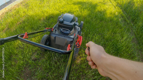 POV: Unrecognizable male gardener starts the lawnmower before cutting grass.