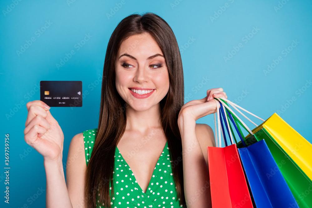 Close up photo of positive cheerful girl hold look credit bank card pay many bags wear style stylish trendy singlet isolated over blue color background - obrazy, fototapety, plakaty 