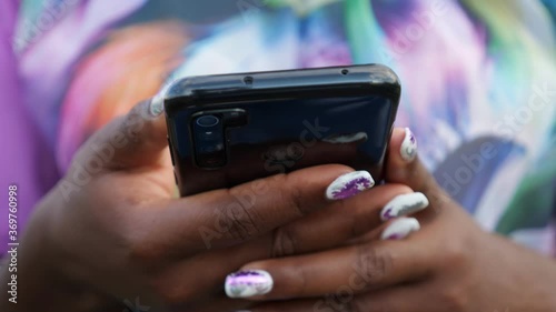 Close-up of black phone in hands of african woman.