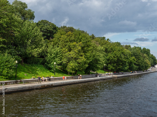 The embankment of the Moscow river. A shady green embankment along a wide river © sablinstanislav