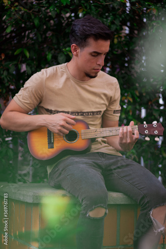 young man plays acoustic instrument in summer 