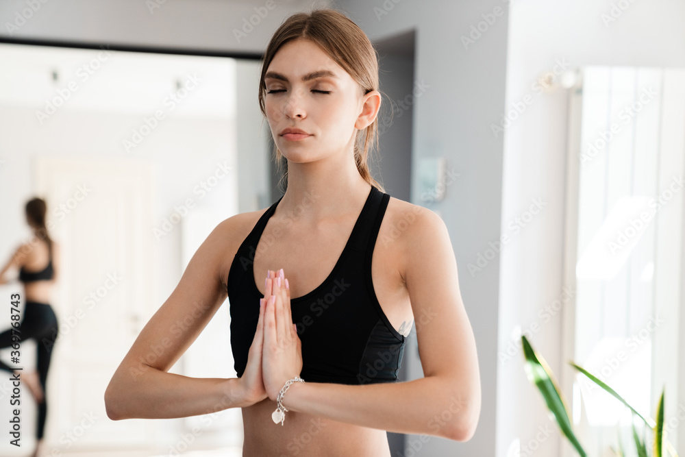 Image of young woman doing yoga exercises while working out at home