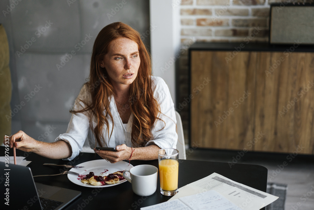 Image of businesswoman working with laptop while having breakfast