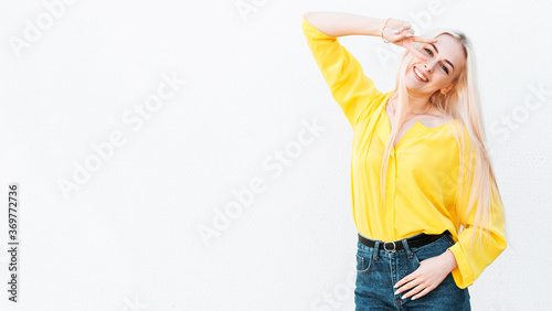 Young happy smiling woman in yellow shirt making victory, positive, peace sign on her eye