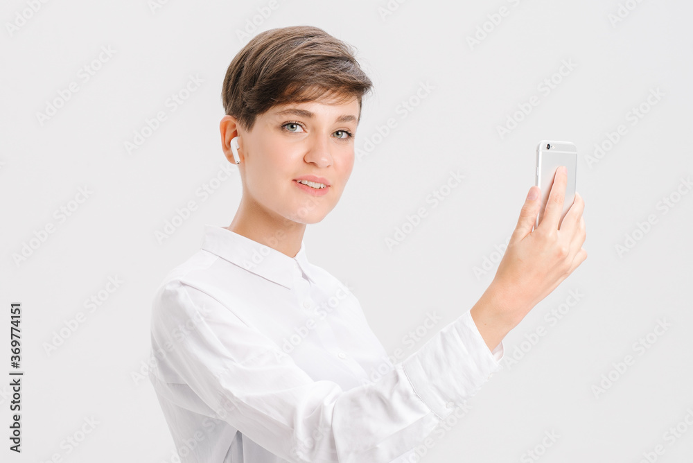 a young woman uses wireless headphones for a video call. white background in studio. online business meeting concept a young woman uses wireless headphones for a video call. white background in studio. online business meeting concept