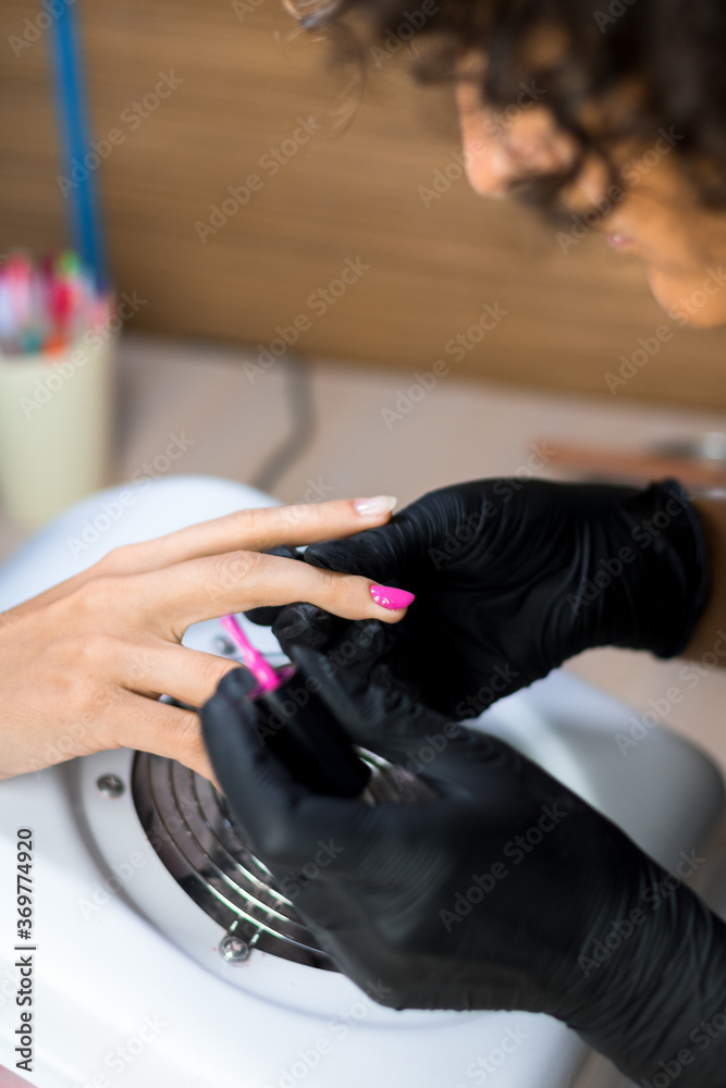 manicurist master in black gloves doing purple manincure in the nail salon