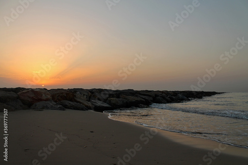 A beautiful and relaxing sunrise on the beach. Orange sky illuminates the breakwater