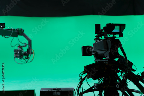 Professional Broadcast studio camera on crane and camera in virtual green studio room with sound equipment on the ceiling.