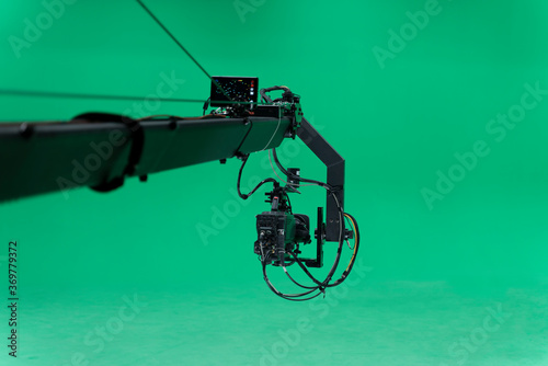 Broadcast television studio camera jib in greenscreen studio room on the ceiling.