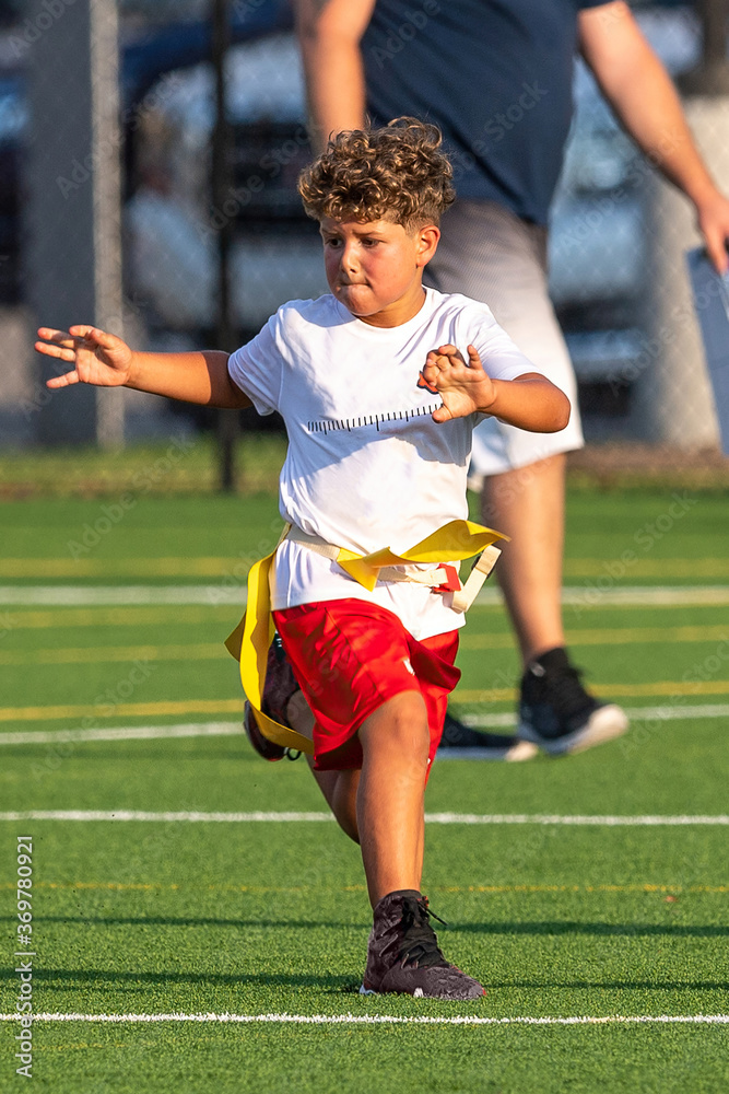 Obraz premium Cute athletic little boy playing excitedly in a flag football game