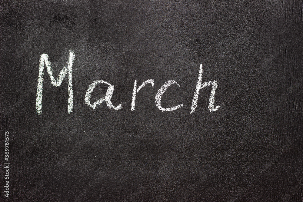 Fototapeta premium Month written in white chalk on a chalkboard. The month depicted on the chalkboard is March