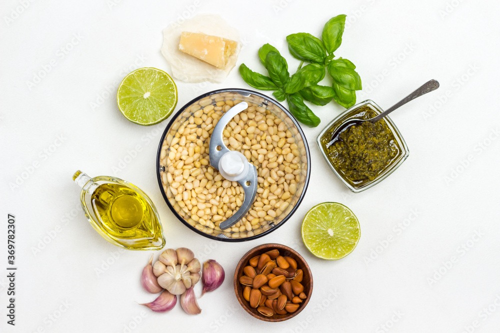 Homemade pesto sauce and ingredients. Cutter with pine nut, unpeeled pine nuts in bowl, olive oil, pesto bowl, basil leaves, parmesan, garlic, lemon. Homemade pesto sauce and ingredients. Cutter with pine nut, unpeeled pine nuts in bowl, olive oil, pesto bowl, basil leaves, parmesan, garlic, lemon.
