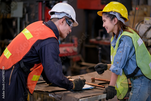 Technician or worker man and woman work together by discussion about their work in the factory with happy emotion. Concept of good management system of industrial business support employee work. © narong