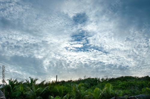 Cloudscape with dramatic overcast sky with sunlight over a tropical land