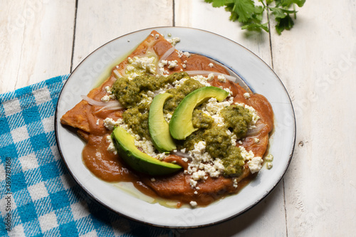 Mexican enfrijoladas with green sauce on white background