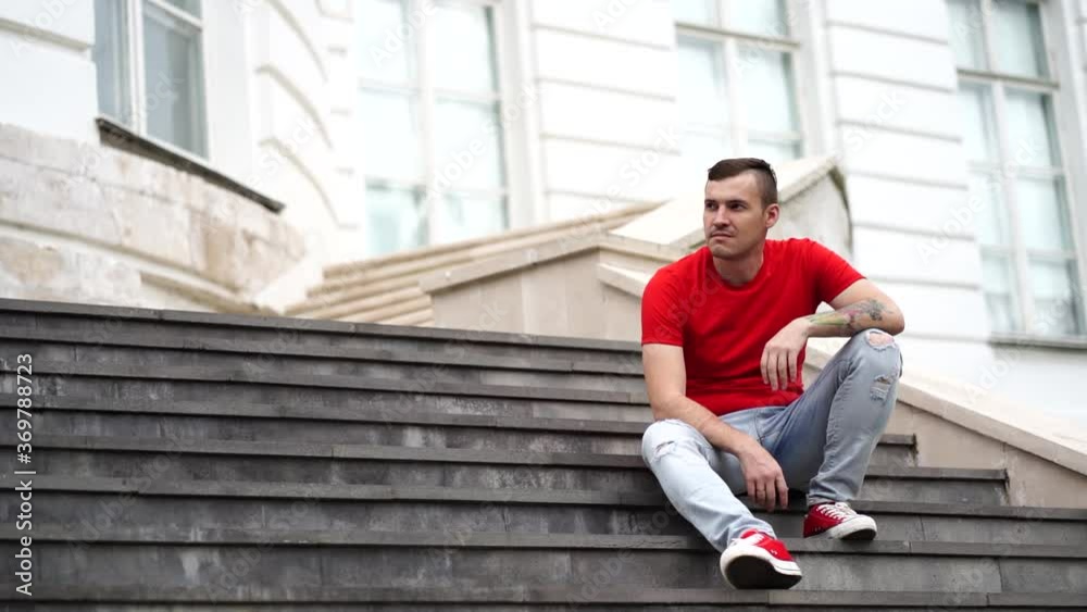 Male tourist sitting on steps of Palace. Young man poses on stairs of manor. Male tourist sitting on steps of Palace. Young man poses on stairs of manor.