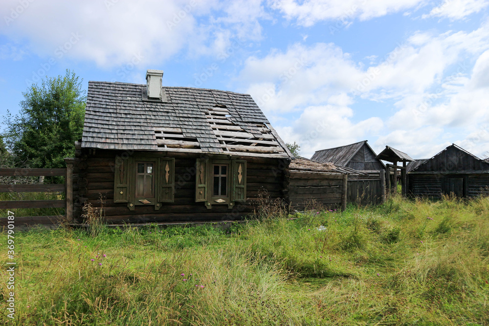 old wooden house in the abandoned village in the green grass under blue summer sky old wooden house in the abandoned village in the green grass under blue summer sky
