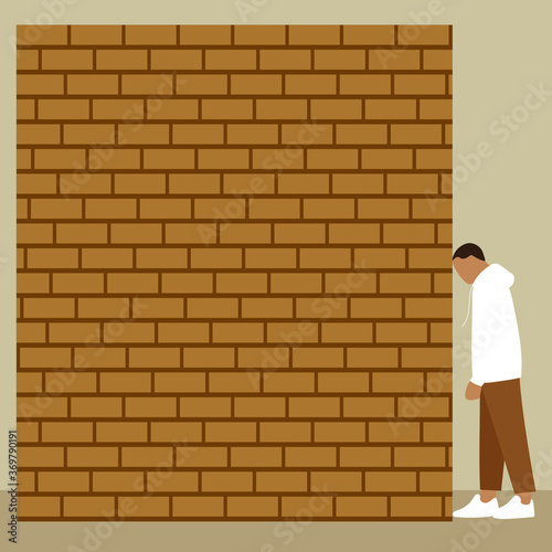 A man rests his forehead against a brick wall