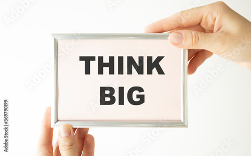 Hands are holding Think big text on a white creative plate.