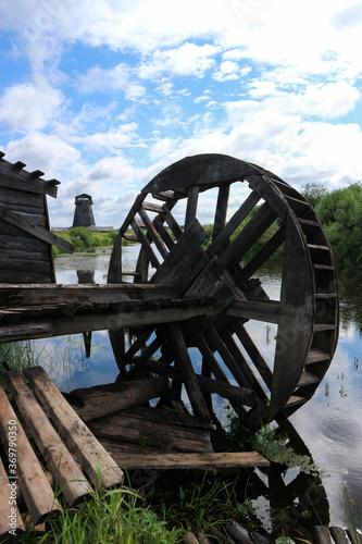 old wooden wheel on the abandoned watermill on the river landscape