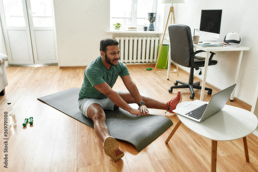 Online trainer. Male fitness instructor showing exercises while streaming, broadcasting video lesson on training at home using laptop. Sport, online gym concept Online trainer. Male fitness instructor showing exercises while streaming, broadcasting video lesson on training at home using laptop. Sport, online gym concept