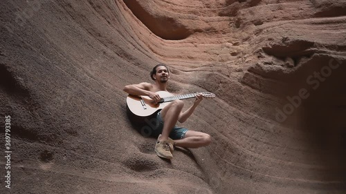 joven músico canta y toca la guitarra dentro de Temisas Canyon. Aguimes. Gran Canaria photo