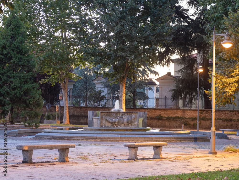 deserted square with stone benches and a beautiful circular fountain.Metropolitan city of Milan, Italy