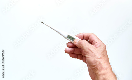 Old man's hands holding digital thermometer to measure body temperature. Means of coronavirus prevention and treatment. Covid-19. Health concept.