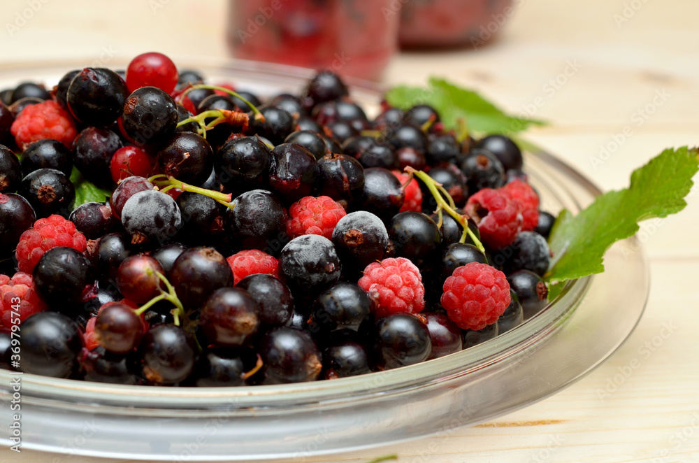 red and black currants and raspberries fresh garden berries on a plate close-up red and black currants and raspberries fresh garden berries on a plate close-up