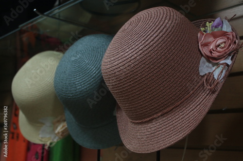Three differently colored panama hats with roses on the sides on display in a small store in South America