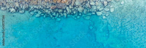 An aerial view of the beautiful Mediterranean Sea, where you can see the cracked rocky textured underwater corals and the clean turquoise water of Protaras, Cyprus, 