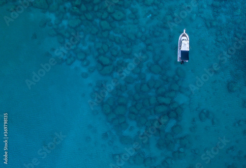 An aerial view of the beautiful Mediterranean Sea and a boat, where you can see   the cracked rocky textured underwater corals and the clean turquoise water of Protaras, Cyprus,  © Valentinos Loucaides