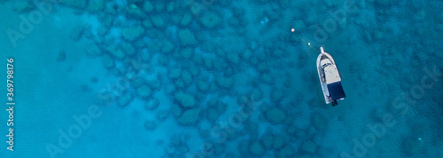 A horizontal aerial view of the beautiful Mediterranean Sea and a boat, where you can see   the cracked rocky textured underwater corals and the clean turquoise water of Protaras, Cyprus, 