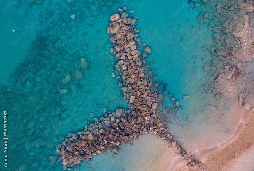 Aerial shot of a crystal clear sea surrounded by rocks making a y shape under the sunlight in Protaras, Cyprus
