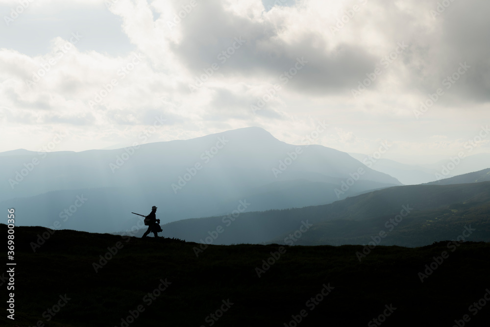 A silhouette of a photographer with a tripod against the backdrop of the majestic mountains. Landscape photography
