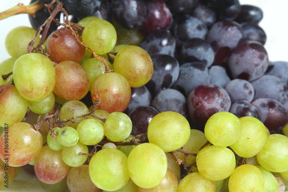 Black and green delicious grapes on a white plate close up Black and green delicious grapes on a white plate close up
