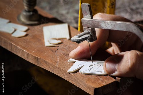 Luthier cutting a M letter mop inlay